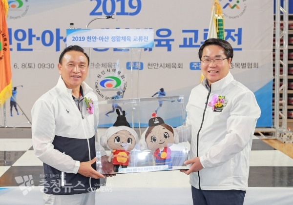 오세현 아산시장과 구본영 천안시장이 기념품을 교환하고 기념촬영을 하고 있다.