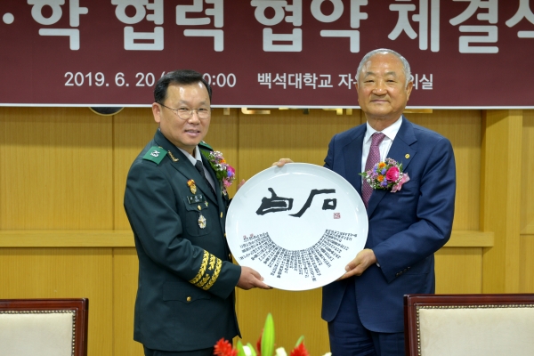 백석대 장택현 대학혁신위원장이 육군대학 서천규 대학장에게 대학 기념품을 전달하고 있다.