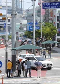 더위를 피해 그늘막을 이용하고 있는 시민들