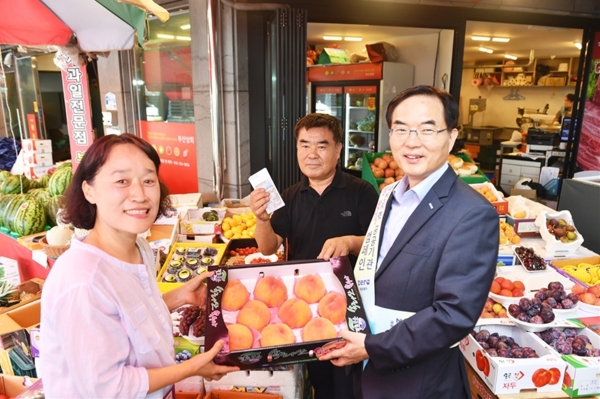 조용만 사장(오른쪽)이 전통시장에서 과일을 구매하고 있다