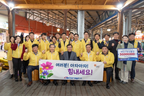 한국서부발전 임직원 및 지역관계자가 지역경제를 활성화하자는 구호를 외치며 기념촬영을 하고 있다.