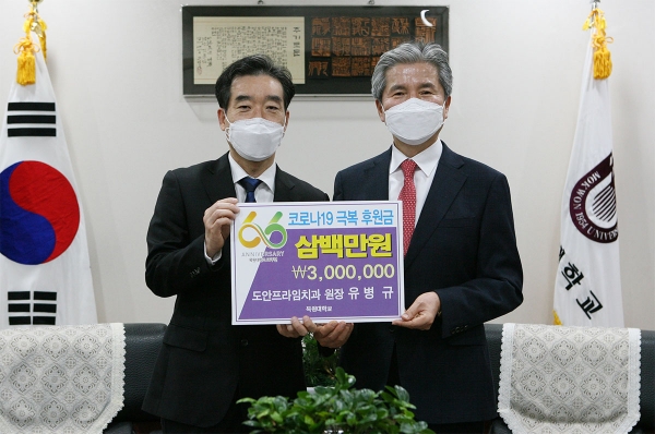 도안 프라임치과의원 유병규 원장(왼쪽)이 권혁대 총장(오른쪽)에게 코로나19 극복 후원금을 전달하고 있다