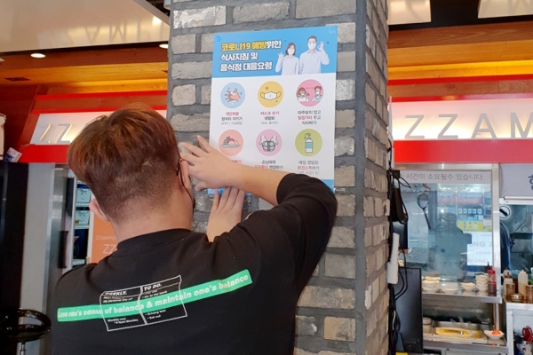 음식점 내부에 코로나19 예방을 위한 식사지침 포스터를 부착하고 있다.