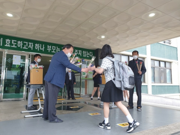 첫 등교를 하는 학생들에게 꽃다발을 나눠주는 김관중 교장 선생님의 모습