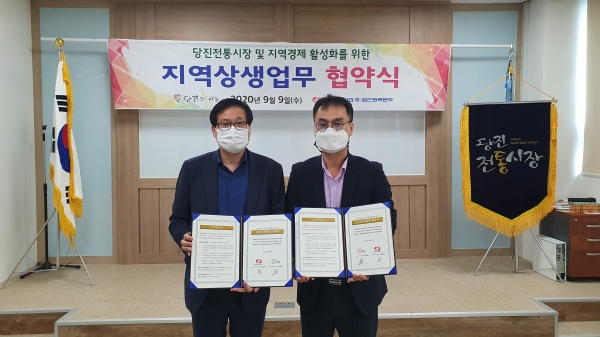 당진전통시장과 온라인 쇼핑몰 '당찬한끼' 지원에 관한 업무협약을 체결/ 김동환 당진화력본부 대외협력실장(왼쪽)과 정제의 당진전통시장협동조합이사장(오른쪽)이 협약서를 들고 포즈를 취하고 있다.