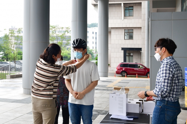 안전헬멧 무상대여(교수회 관계자가 학생에게 안전헬멧을 씌워주고 있다)