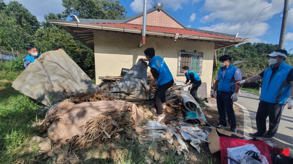 집 옆에 쌓인 쓰레기를 정리하는 농어촌공사 직원들
