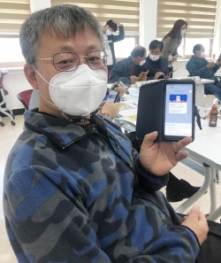 인지면 이장이 온통서산 계정 가입을 들어보이는 장면