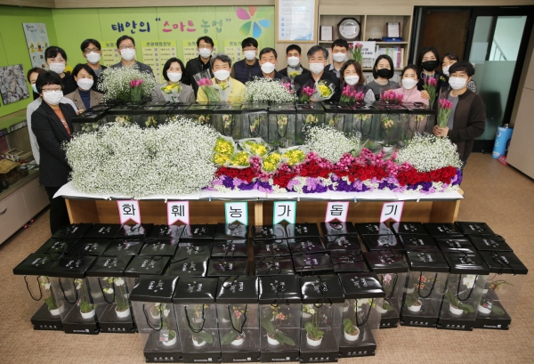 ‘플라워 오피스’를 만들기 위해 구입한 화분 앞에서 기념촬영을 하고 있는 군 농업기술센터 직원들 모습.