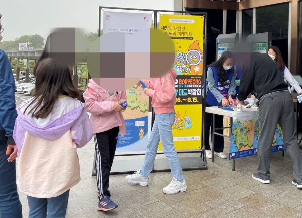 2022보령해양머드박람회 조직위 직원들과 보령시청 박람회 지원단이 시흥하늘휴게소에 홍보부스를 설치하고 일회용 손세정제 티슈와 리플릿, KF94마스크 등을 배포하고 있다.