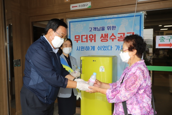 정해명 홍성농협조합장(왼쪽)은 무더위 극복을 위한 폭염냉장고를 본점 객장에 설치하고 농협을 방문한 지역주민에게 시원한 얼음물을 전달하고 있다.