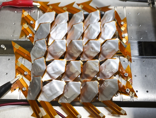 온도 및 환경이 제어되는 유연신축성 배터리 신뢰성 평가 장치를 이용하여 뱀 비늘형 배터리에 기계적 변형을 주면서 충방전 신뢰성을 평가하는 모습을 보여주고 있다.