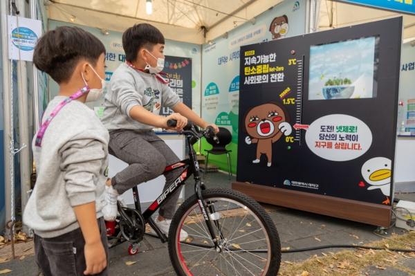 어린이들이 탄소중립 체험부스에서 자전거 발전기를 체험하는 모습