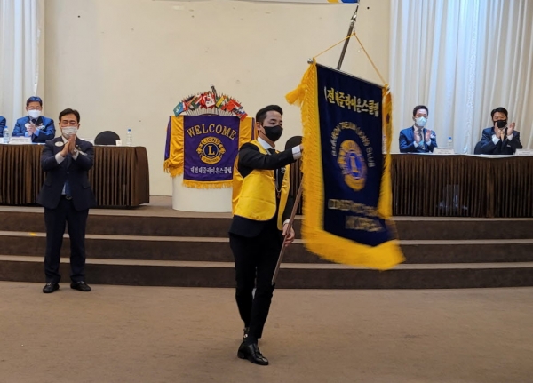 클럽기를 전달 받은 김수기 초대회장이 힘차게 휘두르고 있다.