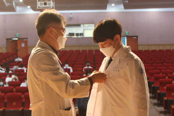 을지대학교 김주헌 교수(좌)가 의학과 이상원 학생(우)에게 가운을 입혀주고 있다.