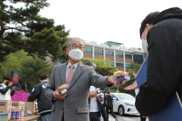한국영상대학교 유재원 총장이 등교케어 행사에서 등교학생들에게 빵과 음료를 나눠주고 있다