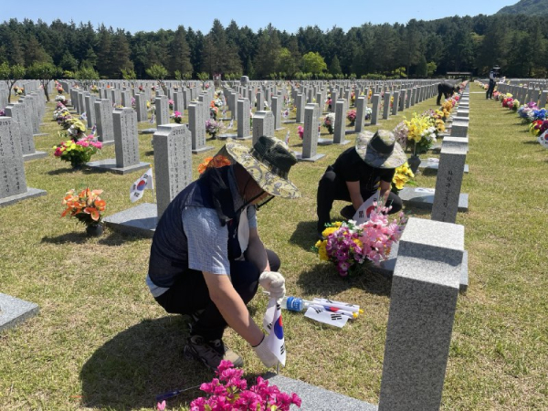 지난 27일 국립대전현충원에서 대전광역시시설공단 직원들이 순국선열 묘역 정화 및 태극기 꽂기 봉사활동을 하고 있다