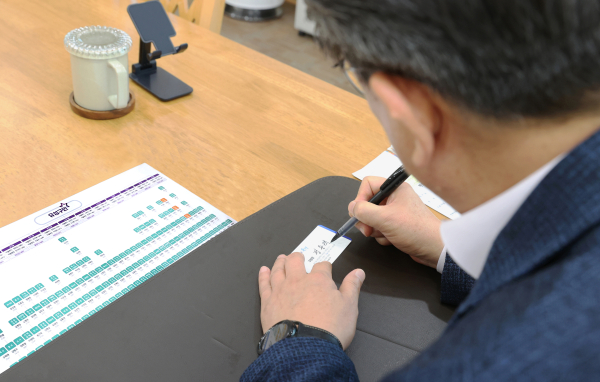 정용래 유성구청장이 초심명함에 본인의 이름 석자를 쓰고 있다.