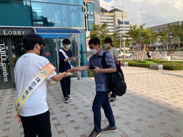 캠페인에 참여한 청소년이 주민들을 상대로 홍보물을 나눠주고 있다.