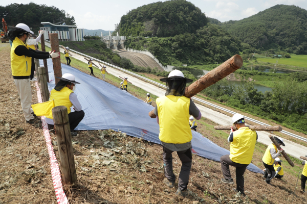 저수지 사면유실로 누수를 막기위해 천막을 덮는 모습