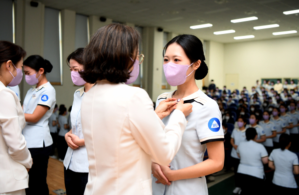 치위생학과 교수가 학생에게 ‘치과위생사핀’을 달아주고 있다.