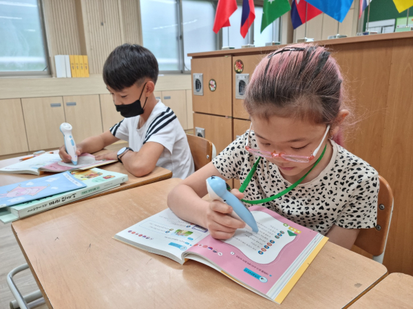 다문화학생들이 다국어 소리펜 교재를 활용하여 한국어학습을 하고 있다