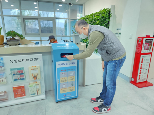 주민이 폐의약품 전용수거함에 사용하지 않는 의약품을 버리고 있다