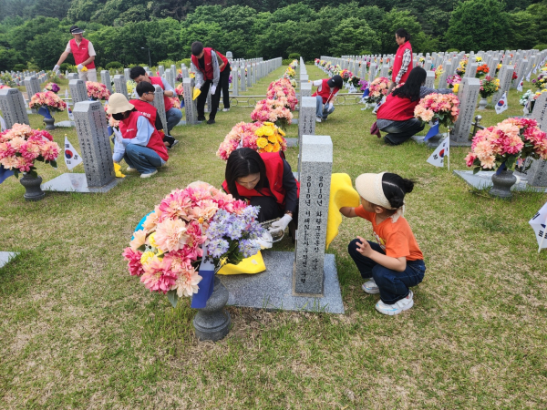 YC청년회의 윤경숙 대표와 한 어린이가 대전국립현충원 천안함 묘역에서 묘비를 닦고 있다.