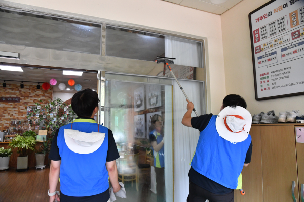한국조폐공사 신입직원이 ‘행복원’에서 유리창 청소하며 봉사활동을 하고 있다.