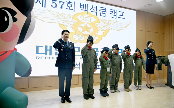 백석쿰캠프에 참가한 어린이들이 공군 조종복을 입고 경례를 하고 있다.