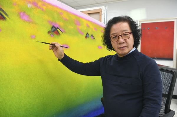 윤천균 화백이 작품 앞에서 붓을 들고 있다.