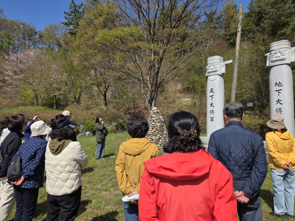2025 지역문화유산 스토리텔링 ‘뚜벅뚜벅 대덕소풍’ 참여자들이 ‘장동 산 따라’ 테마 진행 중 장동 진골 산고개에 위치한 장승 앞에서 전문 해설사의 설명을 듣고 있다.
