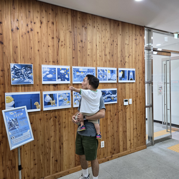 국립대전숲체원 채움관 1층 전시 공간에서「구름공장」원화 전시를 감상하고 있는 방문객 모습.